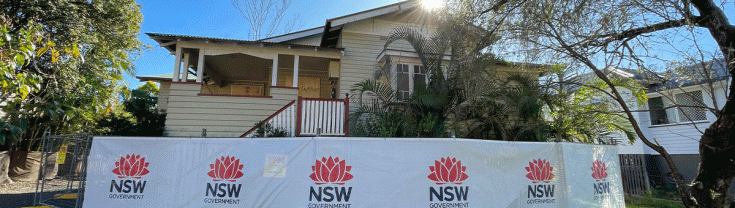 A flood damaged home with a fence around it showing NSW Government signage