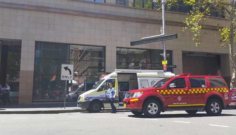 One NSW fire car and police rescue vehicle next to an apartment with a police officer.