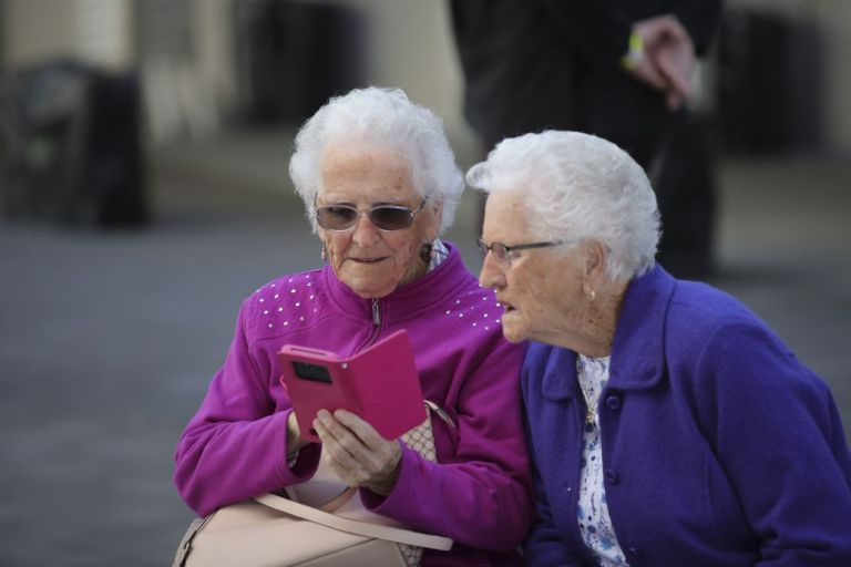 Two senior ladies looking on mobile phone outside seniors expo