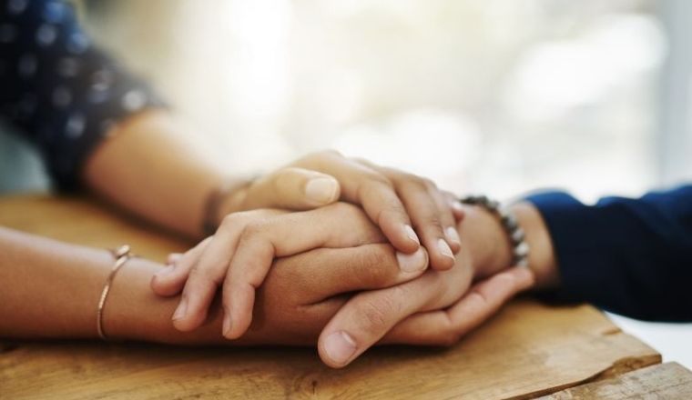 A person's hand holding another person's hand for support.