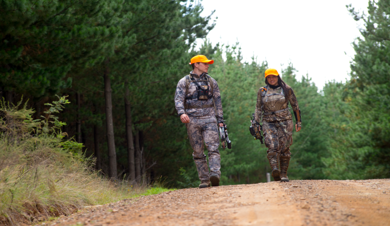 A male and female bowhunter walk down a State forest road