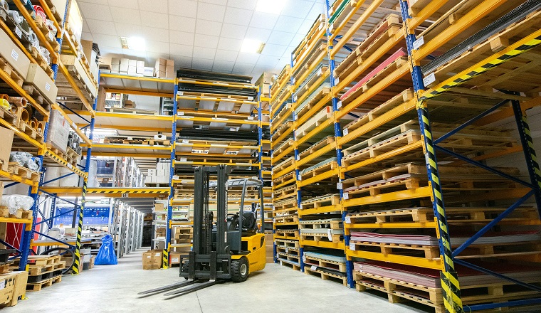A yellow and black forklift is stationary in a large warehouse.