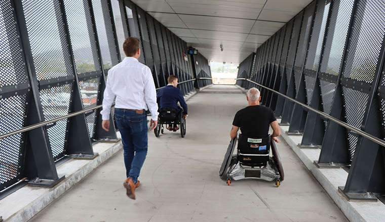 Unanderra wheelchair rugby 3 backs of people going over bridge