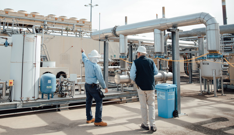 Two male workers inspect newly built gas infrastructure facility during the day