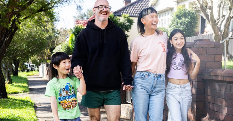 Parents walking with their son and daughter down a footpath outside suburban houses