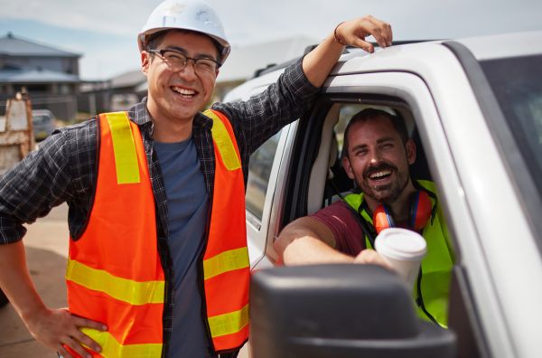Two constructions workers in high res jackets with one worker in a ute 