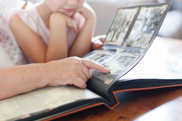 Grandmother and young grand daughter looking through old family album