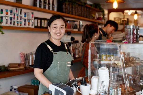 A cafe owner wearing a striped apron in her own business