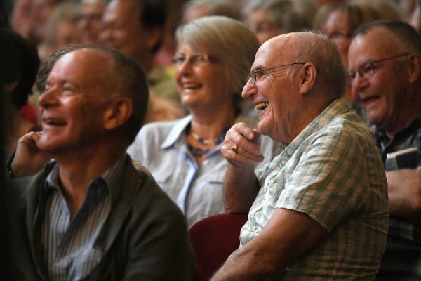 Man and woman bursting with laughter as they watch stage at Seniors Comedy Show