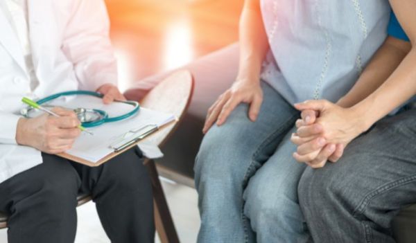 A man and woman are seated near a doctor discussing fertility option