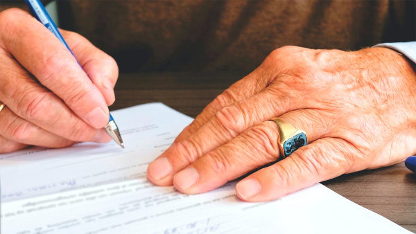 Elderly persons hands with a pen signing a document