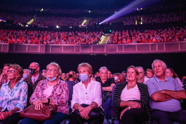 Photo of a full theatre of seniors at the 2022 Premier's Gala Concerts. Concert-goers are cast in a pink-red glow lighting. 