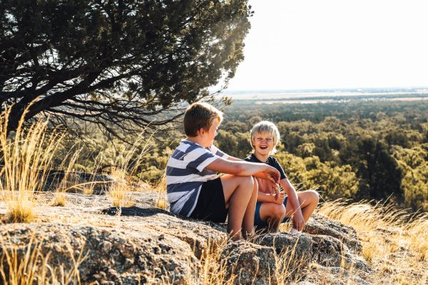 two boys sitting on a hill overlooking regional NSW