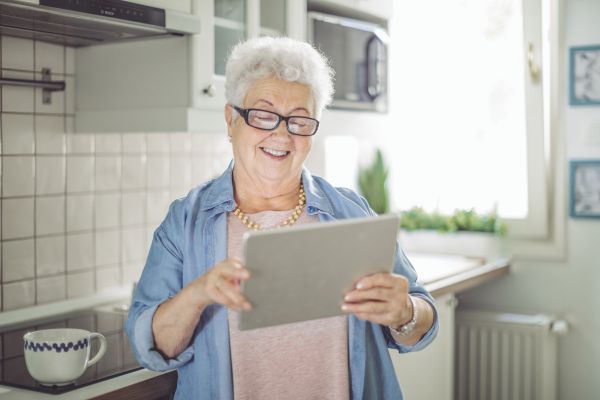 Senior woman in her kitchen, looking at an iPad