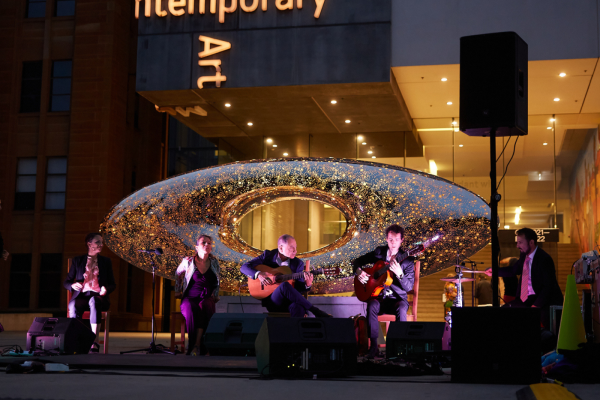 A live 5 piece band playing outside the Museum at night time
