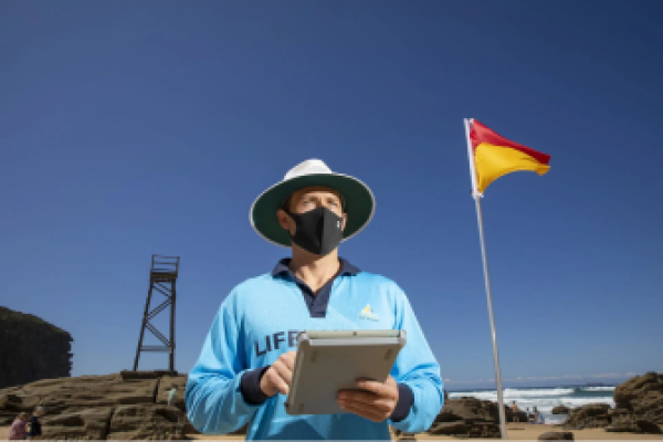 Surf Lifesaver holding a tablet device to monitor surf conditions