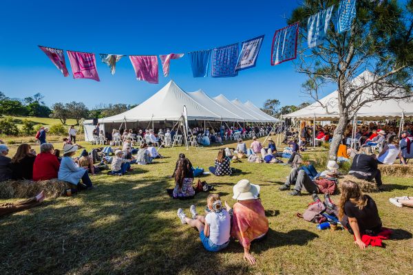 Audience sitting on grass under blue sky at Byron Writers Festival
