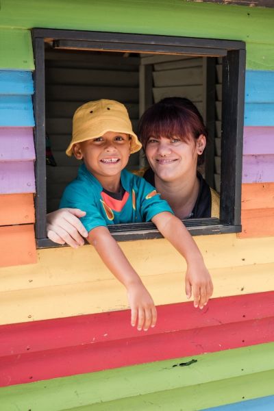 Young boy and preschool teacher looking out of cubby house window