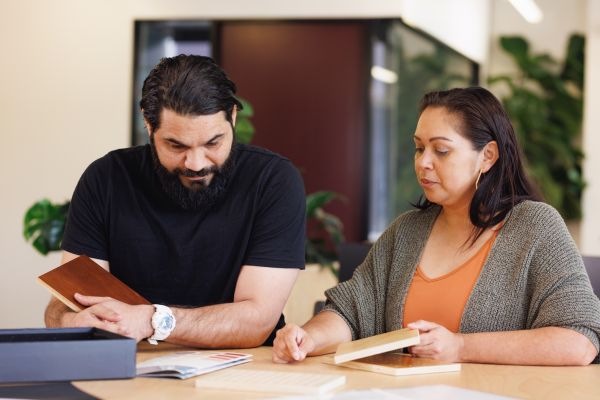 An aboriginal man and woman sit at a desk in an office looking at papers