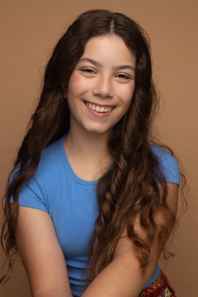 Young girl in a blue t-shirt and long wavy hair smiling at the camera