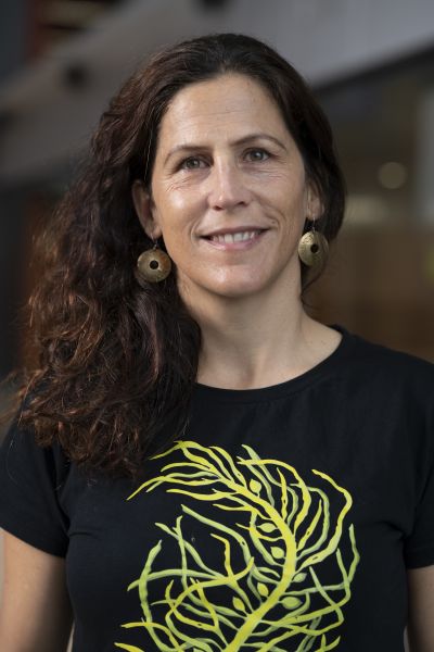 Woman with curly hair, wearing a black t-shirt with a tree branch on it