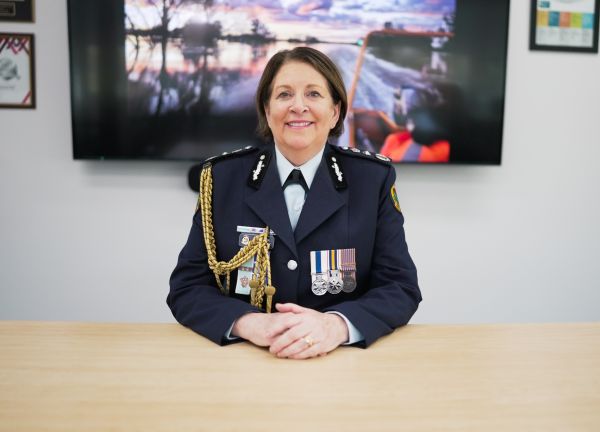 Woman with short hair and a uniform with medals displayed sits poised