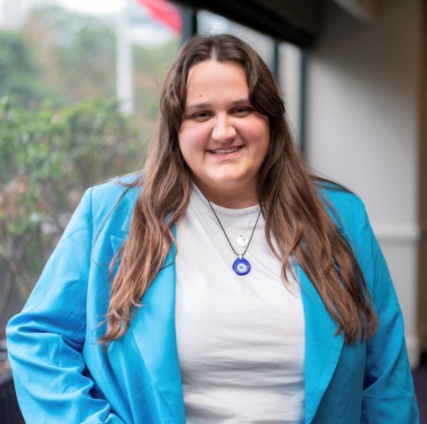 A young woman in a bright blue blazer and white shirt with long hair and a soft smile