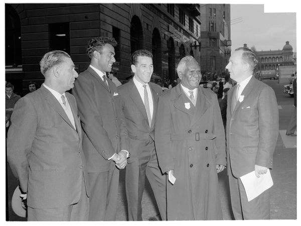 A historical photo in black and white of group of first nations and european men in suits 