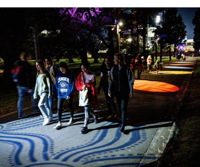 Minister Jo Haylen and students from Sydney Girls High School walk along the pathway with lighting installations that they helped design for the Moore Park Safer Cities project.