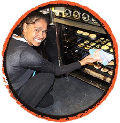 Decorative image of a smiling aboriginal woman removing baked items from an oven
