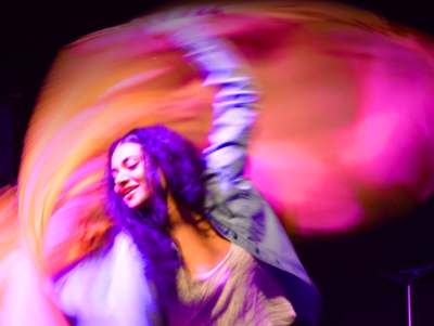 A woman is dancing while holding a pink/orange scarf