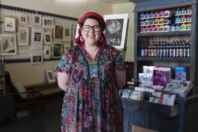 A colourfully dressed woman smiling in an arts supply store