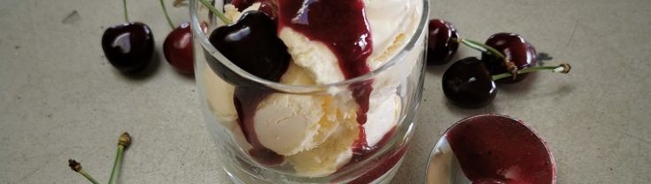 Ice-cream in a glass with cherry coulis and fresh cherries