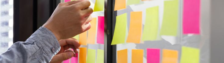 Man attaching sticky note to task board in the office