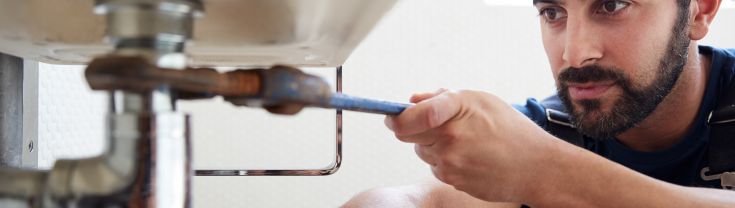 Image of a man working to repair a leaking tap