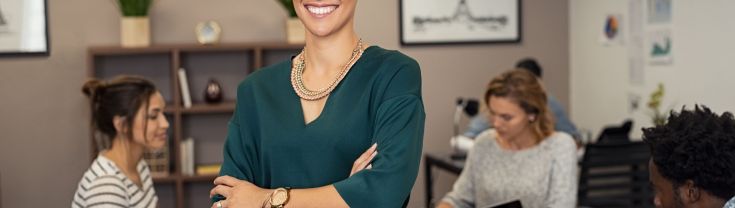 Smiling woman in office with colleagues in background