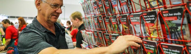 Man browsing through a wall of brochures at Seniors Expo