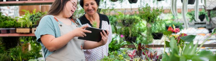 Young worker and manager looking at a tablet working in a garden centre