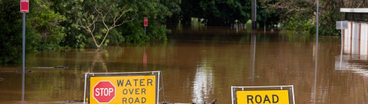 Flooded road with warning signs protruding above water line