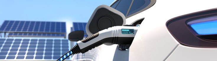 electric car with plug recharging - with solar panels in background