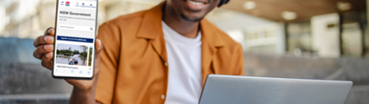 A man smiling, holding a smart phone