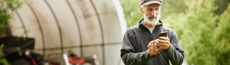 Image of older man on a farm holding mobile phone
