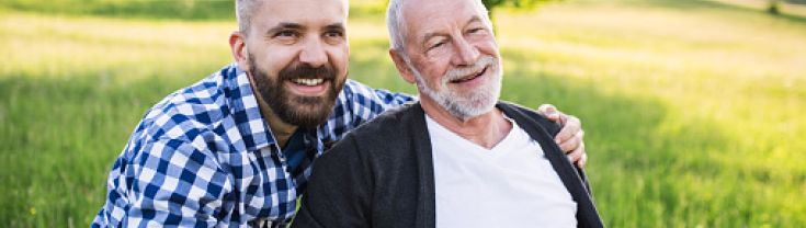 Son with arms around dad as they enjoy the day out in a field