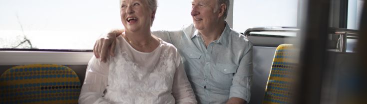 Older couple sitting on train smiling 