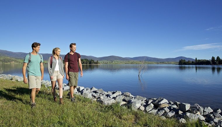 Three people walking by a lake