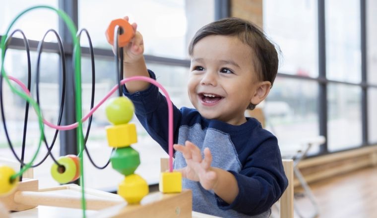 Toddler boy playing with toys in a preschool room