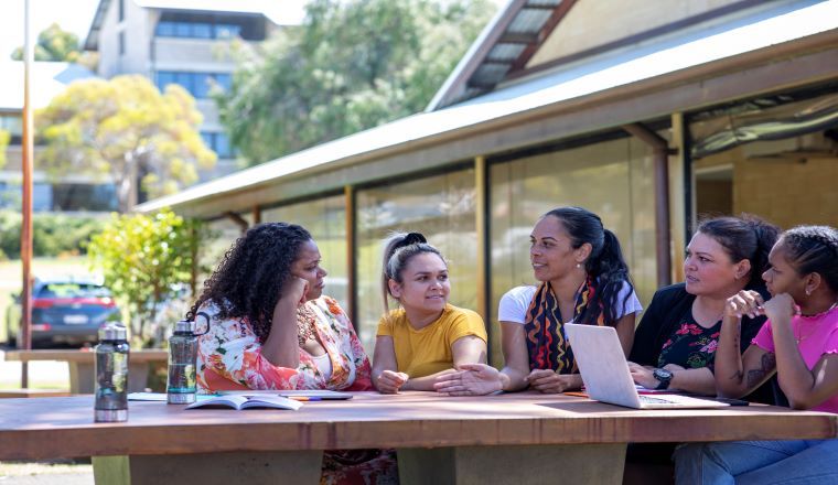 Group of young female aboriginal students sitting outdoors in the sun in Australia.