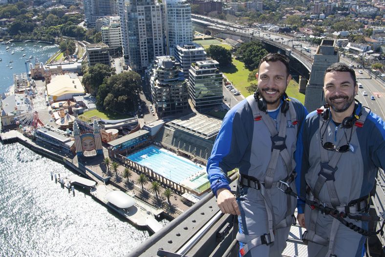 Couple climbing the Sydney Harbour Bridge over looking city views