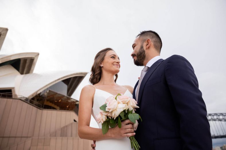 Bride and Groom smiling at each other outside the Sydney Opera House