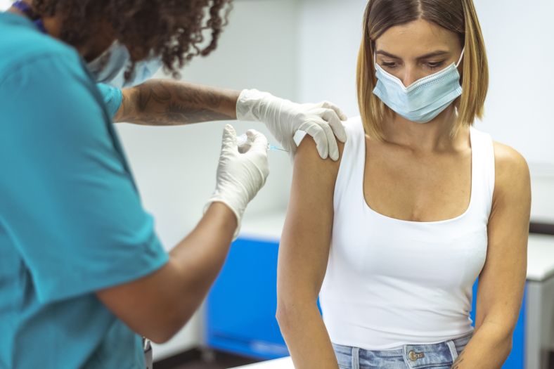 Young woman being vaccinated by a health professional. 
